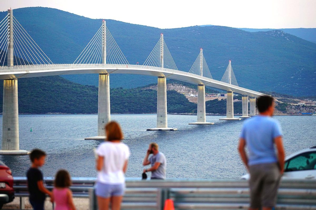 Chinese-Built Bridge Connects Croatia's Mainland to Its Peljesac Peninsula Visitors at the Peljesac Bridge, that spans the Neretva channel between the mainland and the peninsula of Peljesac, in Dubrovnik-Neretva county, Croatia, on Monday, July 25, 2022. The 2.4-kilometer long four-lane bridge, built by China Communications Construction Group Ltd. and financed by the European Union, officially opens on July 26 and connects the entire southernmost region of Croatia to the rest of the country, bypassing the coastal stretch that gives sea access to Bosnia-Herzegovina. Photographer: Oliver Bunic/Bloomberg via Getty Images