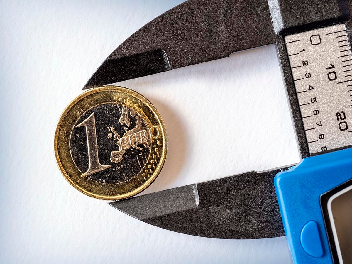 Pressure tool catches a euro coin on a white background. Concept of crisis in the countries of the euro zone.