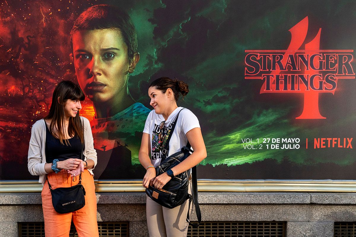 Women talk in front of a street commercial advertisement MADRID, SPAIN - 2022/05/27: Women talk in front of a street commercial advertisement banner from the American global on-demand Internet streaming media provider Netflix featuring Stranger Things Season 4 TV show in Spain. (Photo by Xavi Lopez/SOPA Images/LightRocket via Getty Images)
