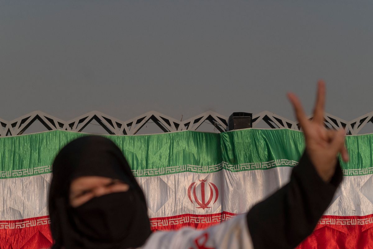 A veiled Iranian woman flashes a Victory sign as she stands in front of an Iran flag during a pro-government protest rally in southern Tehran, December 29, 2022. Pro-government protest rally held in support of Iran's Supreme Leader Ayatollah Ali Khamenei and in opposition to recent unrest following the death of Mahsa Amini, a 21-year-old Iranian-Kurd.
