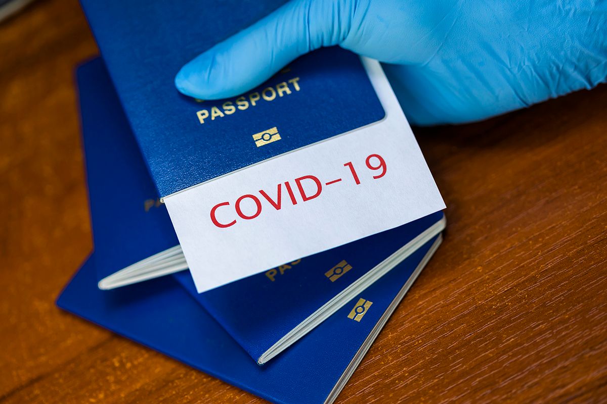 Immunity passport or risk-free certificate concept. Traveling After the Coronavirus Pandemic Man holding a passport with COVID-19 sign stamped onto a white paper, immunity passport or risk-free certificate concept, recovered Coronavirus COVID19 patients being issued proof of convalescence