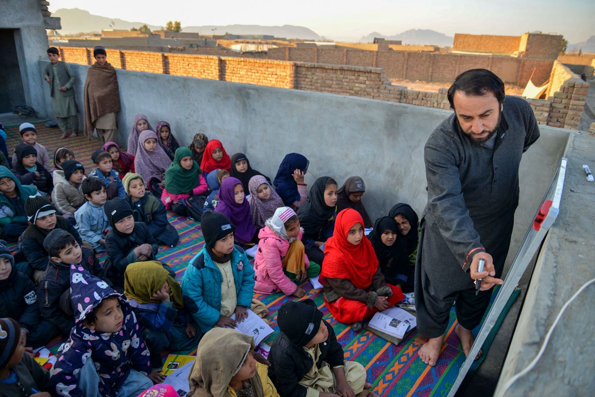 Afghan children take lessons at an open classroom in Dand district of Kandahar province on January 1, 2023.