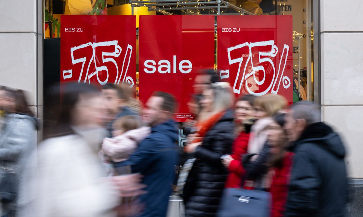 27 December 2022, Bavaria, Munich: Passers-by walk past a shop window in the downtown pedestrian zone that reads "75% Sale." Photo: Sven Hoppe/dpa 