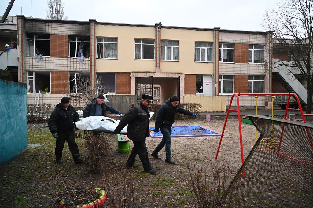 EDITORS NOTE: Graphic content / Four men carry a bag with a body at the site where a helicopter crashed near a kindergarten in Brovary, outside the capital Kyiv, killing Sixteen people, including two children and Ukrainian interior minister, on January 18, 2023, amid the Russian invasion of Ukraine. (Photo by Sergei Supinsky / AFP)