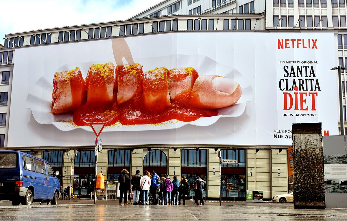 Protest against advertisement A cut up finger in the shape of a currywurst can be seen on an advertisement from US American streaming service Netflix at Potsdamer Platz in Berlin, Germany, 21 February 2017. The poster is an advertisement for the new Netflix zombie series 'Santa Clarita Diet.' The various posters have not been met with enthusiasm everywhere. Due to several complaints received by the German advertising council, Netfilx must now remove several banners. Photo: Paul Zinken/dpa | usage worldwide   (Photo by Paul Zinken/picture alliance via Getty Images)