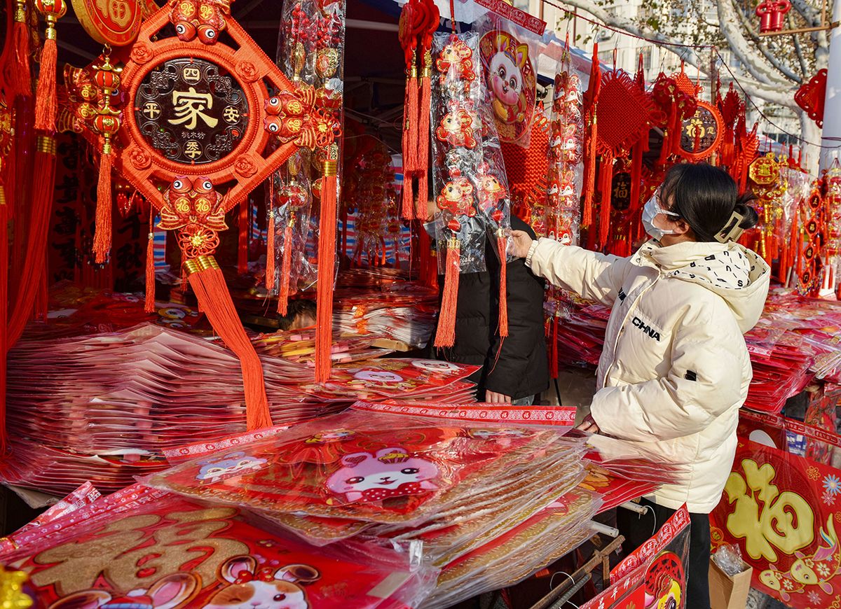 A female customer selects Spring Festival couplets and FUYANG, ANHUI, CHINA - 2023/01/11: A female customer selects Spring Festival couplets and decorations in Fuyang for the Chinese Lunar New Year which falls on January 22 this year. (Photo by Sheldon Cooper/SOPA Images/LightRocket via Getty Images)