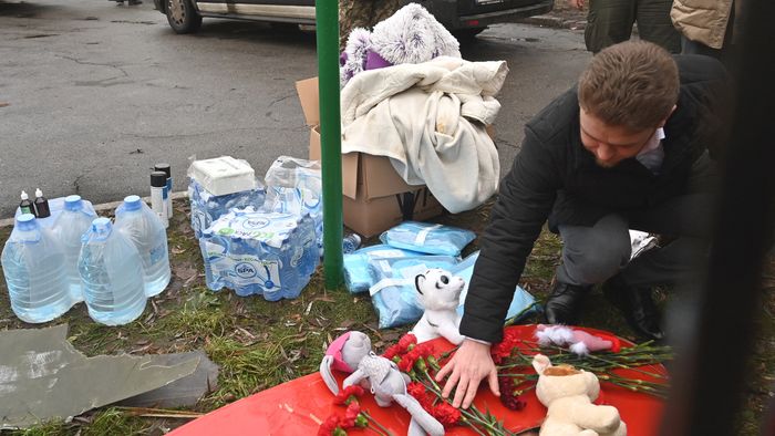 A man lays flowers at the site where a helicopter crashed near a kindergarten in Brovary, outside the capital Kyiv, killing Sixteen people, including two children and Ukrainian interior minister, on January 18, 2023, amid the Russian invasion of Ukraine. (Photo by Sergei Supinsky / AFP)