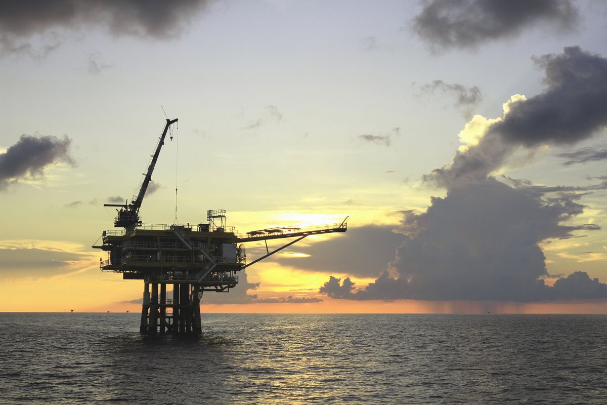 Offshore oil and gas wellhead platform sunset background.