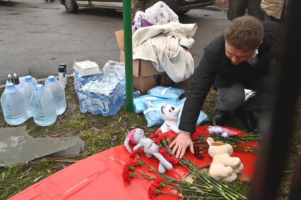 A man lays flowers at the site where a helicopter crashed near a kindergarten in Brovary, outside the capital Kyiv, killing Sixteen people, including two children and Ukrainian interior minister, on January 18, 2023, amid the Russian invasion of Ukraine. (Photo by Sergei Supinsky / AFP)