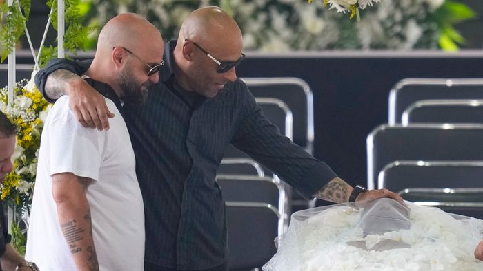 Santos, 2023. január 2.Edinho, Edson Arantes do Nascimento, közismert nevén Pelé háromszoros világbajnok brazil labdarúgó fia (b2) megérinti édesapja homlokát a santosi Vila Belmiro stadionban felállított ravatalnál 2023. január 2-án. A ravatal előtt 24 órán keresztül bárki leróhatja kegyeletét, temetése január 3-án lesz. Pelé 2022. december 29-én, 82 éves korában hunyt el. Jair Bolsonaro, a hivatalából távozó brazil elnök háromnapos nemzeti gyászt rendelt el a tiszteletére.