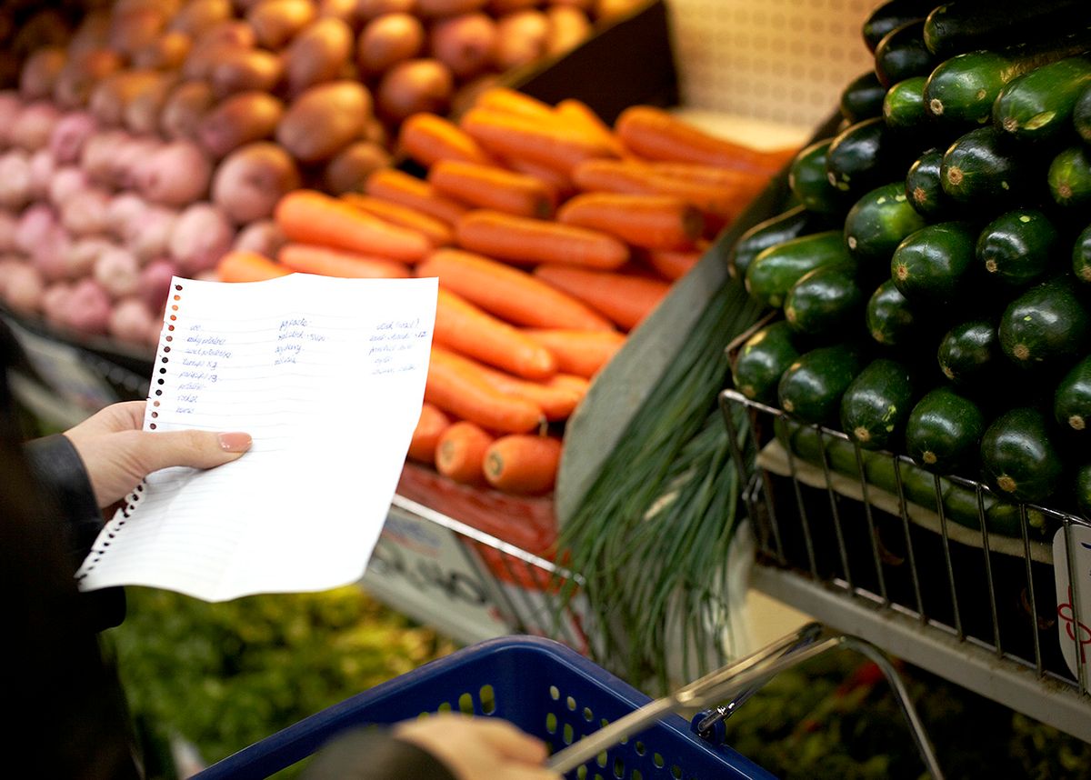 Hand holding shopping list in market
infláció