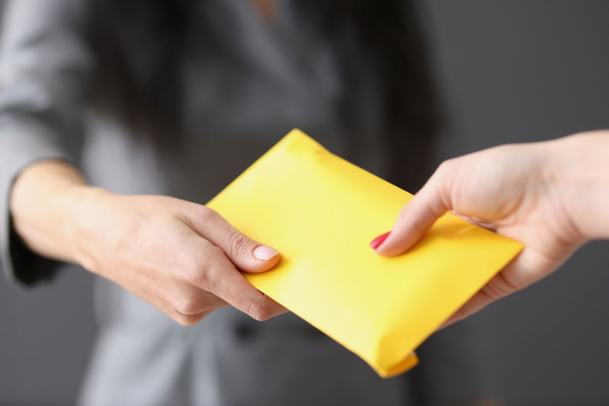 Woman hands yellow closed envelope with money to employee Woman hands yellow closed envelope with money to employee. Fraud and premiums in envelopes concept