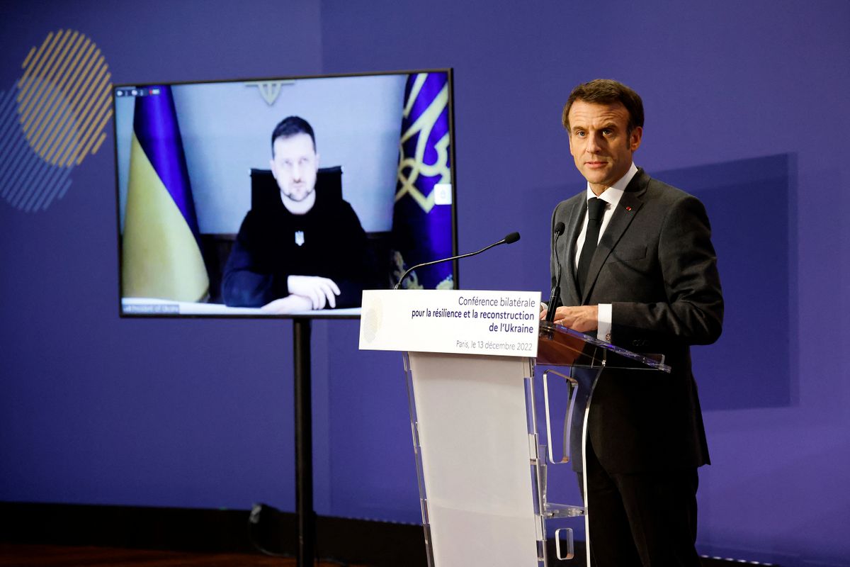 Ukrainian President Volodymyr Zelensky (L) is displayed on a TV screen next to French President Emmanuel Macron delivering a speech during the French-Ukrainian conference for resilience and reconstruction at the Ministry of Economy in Paris on December 13, 2022. 
