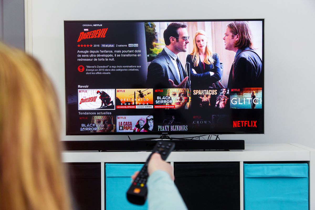 Benon, France - January 21, 2018: Woman Holding a TV remote control and play Dardevil, a Marvel film that is an original creation of Netflix industry. 