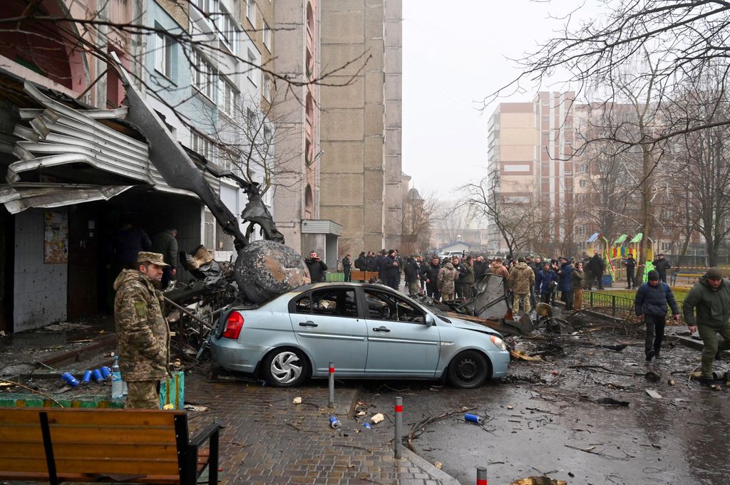 Military and onlookers stand at the site where a helicopter crashed near a kindergarten in Brovary, outside the capital Kyiv, killing Sixteen people, including two children and Ukrainian interior minister, on January 18, 2023, amid the Russian invasion of Ukraine. (Photo by Sergei Supinsky / AFP)