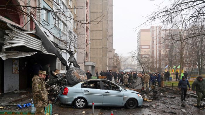 Military and onlookers stand at the site where a helicopter crashed near a kindergarten in Brovary, outside the capital Kyiv, killing Sixteen people, including two children and Ukrainian interior minister, on January 18, 2023, amid the Russian invasion of Ukraine. (Photo by Sergei Supinsky / AFP)