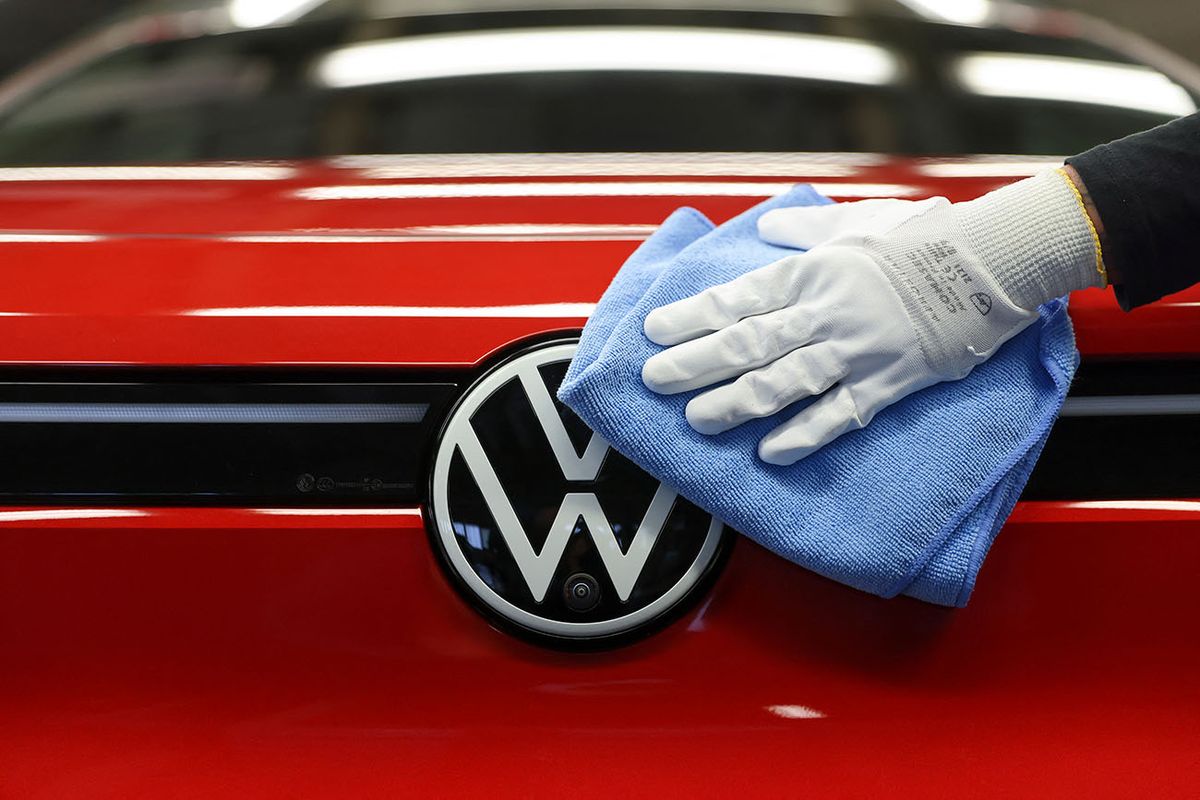 Production of e-vehicles at VW in Zwickau 26 April 2022, Saxony, Zwickau: An employee wipes over the VW logo on an ID.4 in the light tunnel at Volkswagen's plant in Zwickau. In addition to VW vehicles, vehicles from the Group's Audi and Seat brands also come off the production line at the plant. The vehicles are based on the Modular Electric Toolkit. Volkswagen has converted the site, which employs around 9,000 people, into a purely electric vehicle factory at a cost of 1.2 billion euros. Photo: Jan Woitas/dpa (Photo by JAN WOITAS / DPA / dpa Picture-Alliance via AFP)