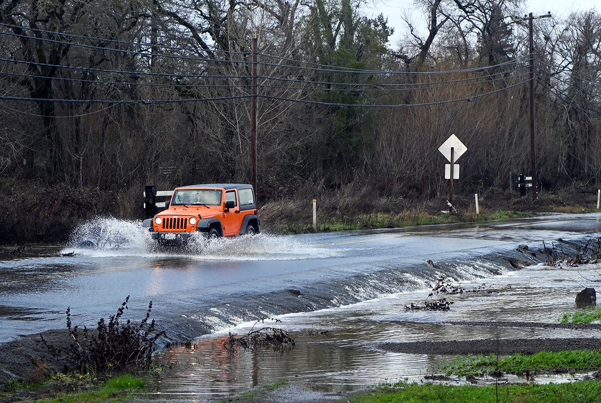 A vehicle drives on a flooded road in Sebastopol, California, on January 5, 2023. - Excessive rain, heavy snow and landslides are expected to wallop California through Thursday as a series of winter storms rip across the western US coast, prompting Governor Gavin Newsom to declare a state of emergency. (Photo by JOSH EDELSON / AFP)