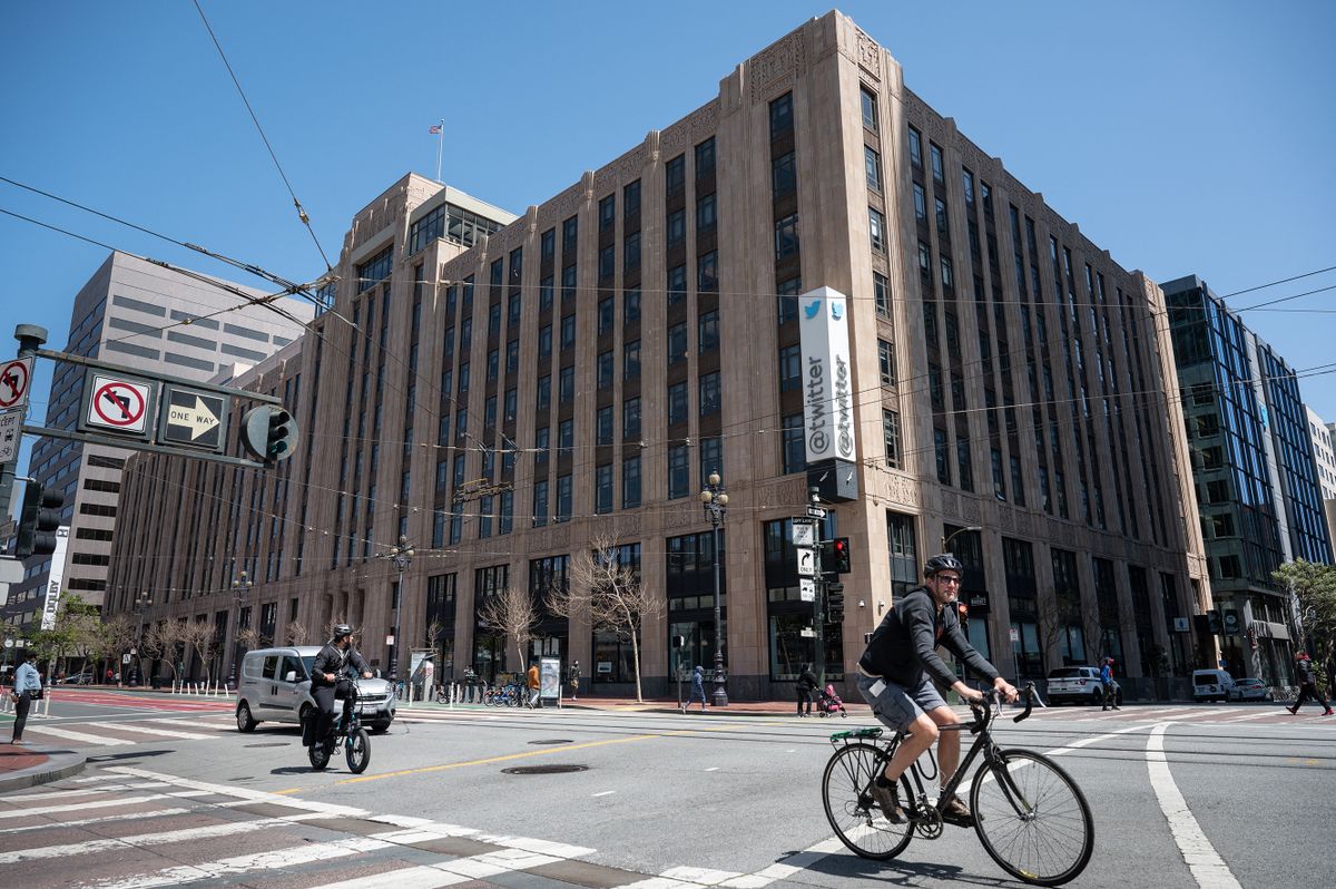 A person cycles past the Twitter headquarters on April 26, 2022 in downtown San Francisco, California. - Billionaire Elon Musk is capturing a social media prize with his deal to buy Twitter, which has become a global stage for companies, activists, celebrities, politicians and more. 