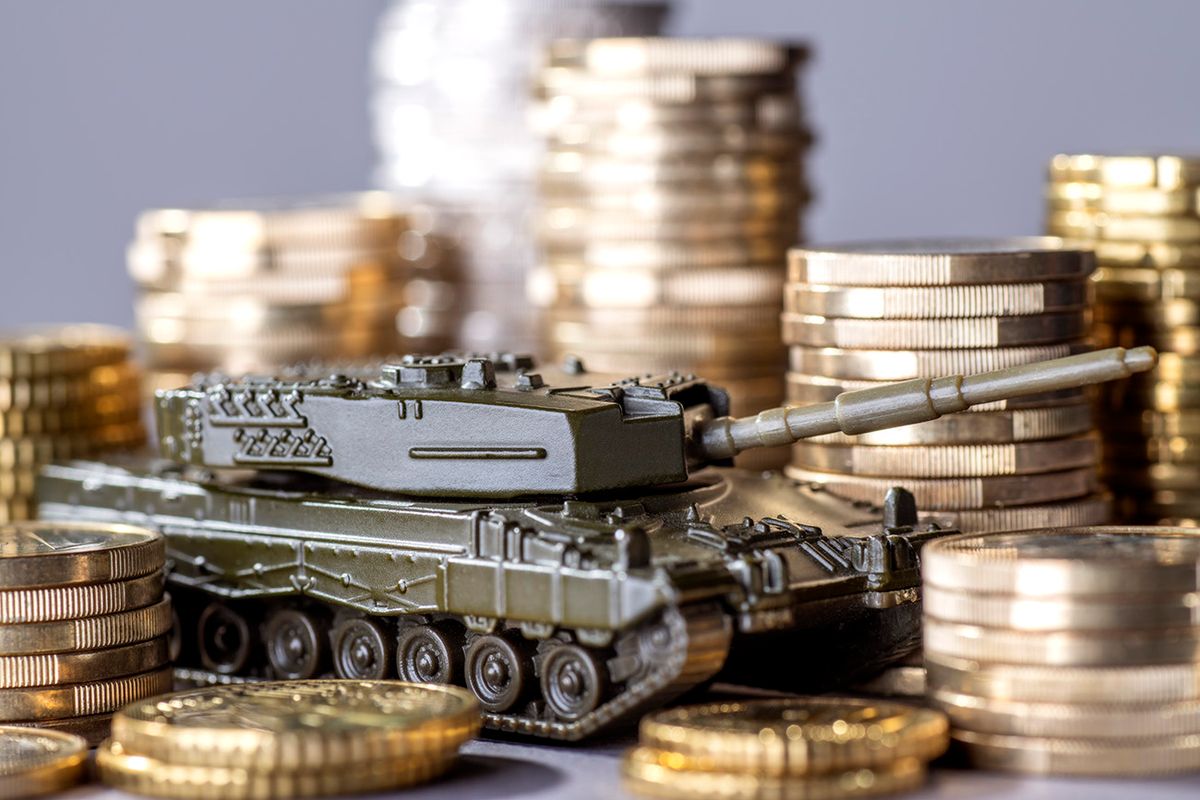 A lot of money for armament Tank between stacks of coins as a symbol of high armament expenditure