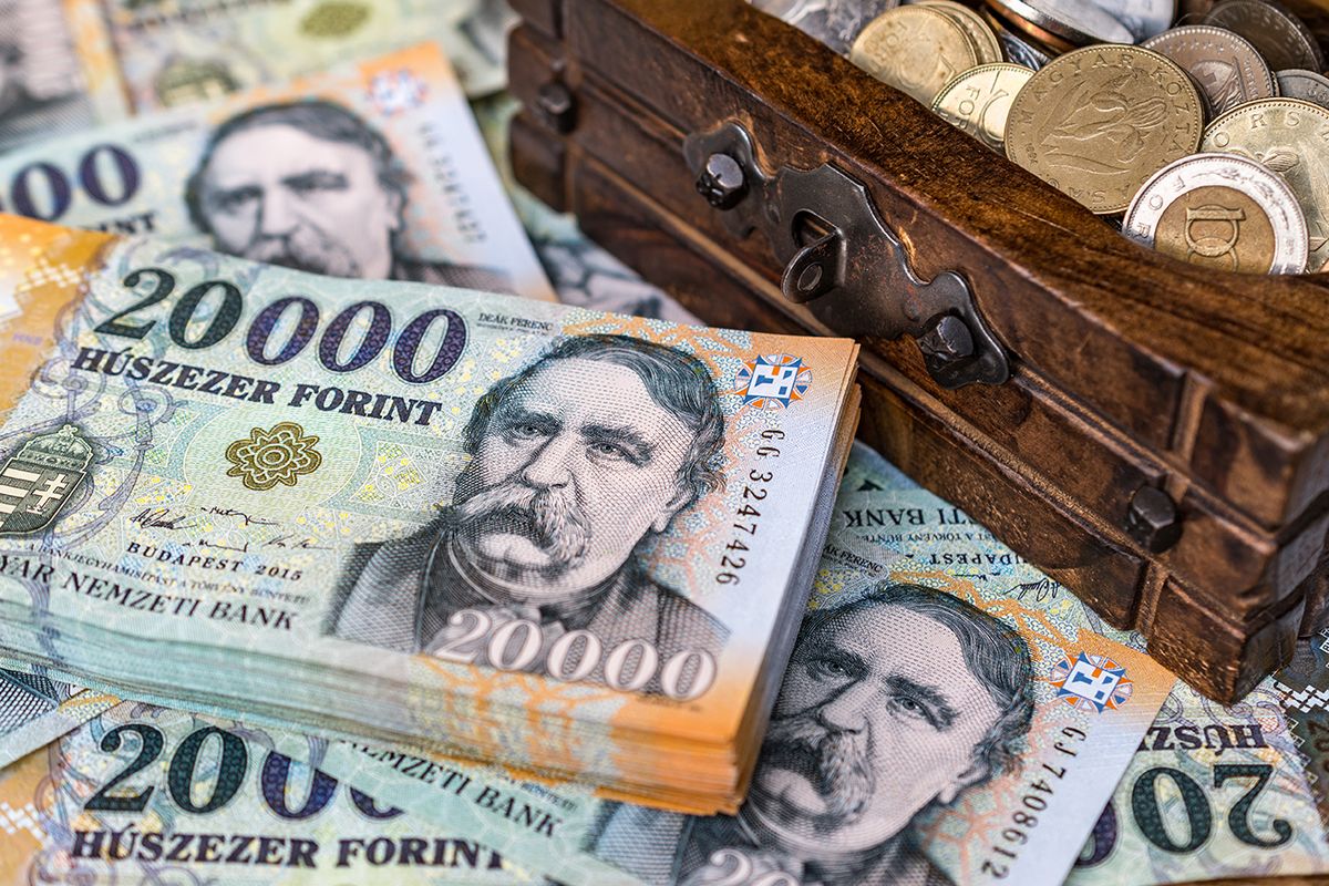 Stack of Hungarian 20000 forint banknotes with an opne vintage wooden box full of coins Concept of wealth, personal savings and collecting money for retirement