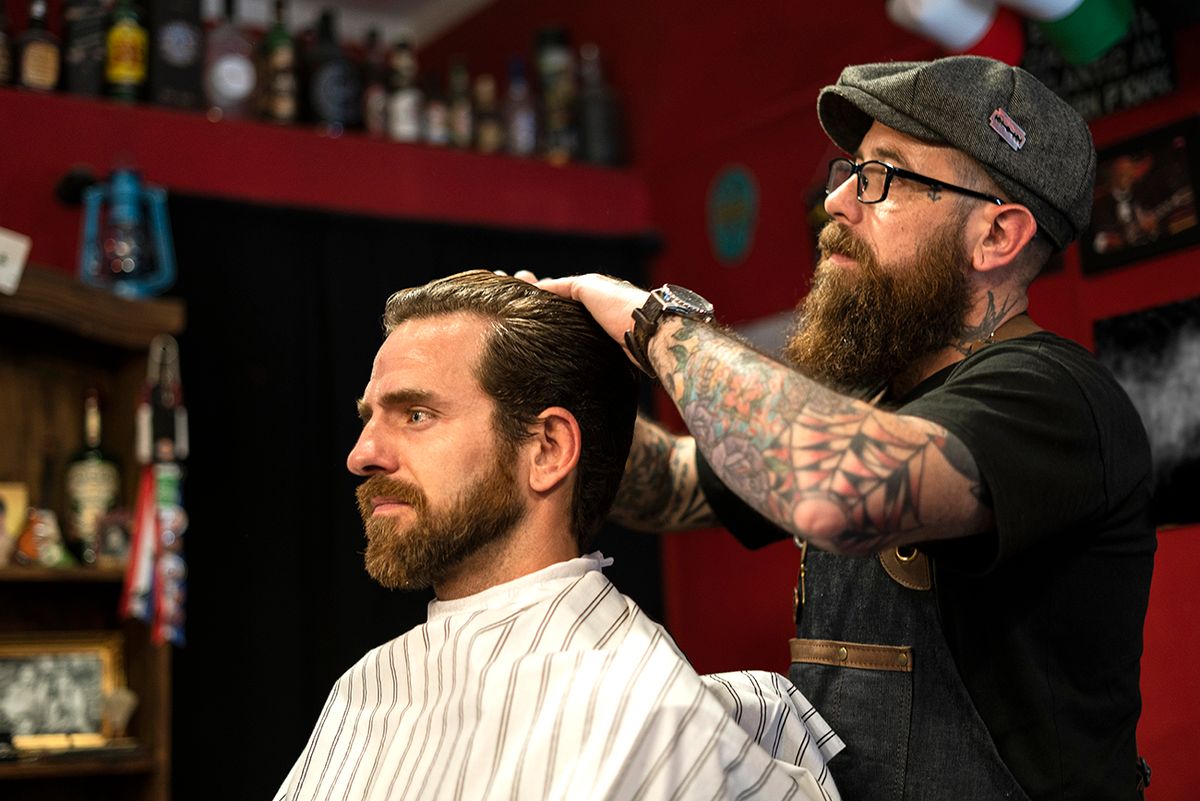 Hairdresser styling man's hair in salon Side view of hairdresser styling man's hair in salon