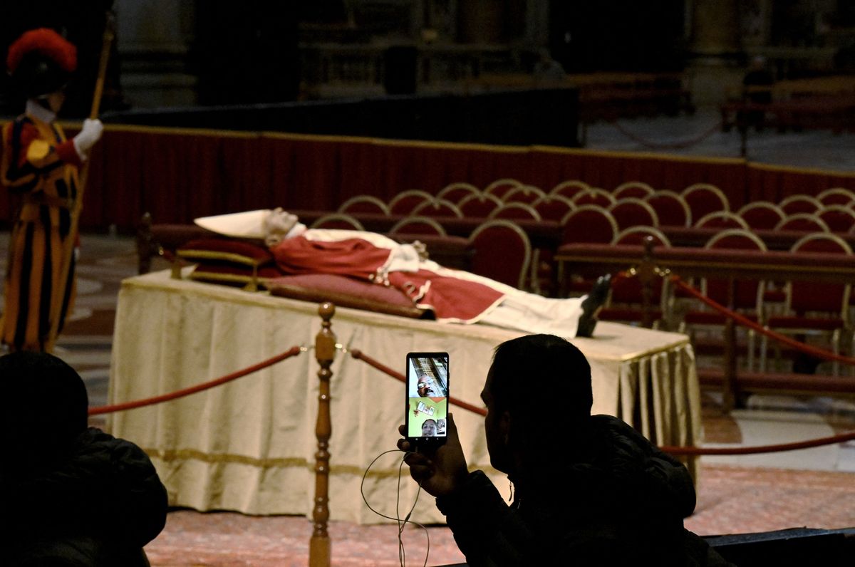 EDITORS NOTE: Graphic content / A man takes a video of the body of Pope Emeritus Benedict XVI laying in state at the St. Peter's basilica in the Vatican, on January 2, 2023. - Benedict, a conservative intellectual who in 2013 became the first pontiff in six centuries to resign, died on December 31, 2022, at the age of 95. Thousands of Catholics began paying their respects on January 2, 2023 to former pope Benedict XVI at St Peter's Basilica at the Vatican, at the start of three days of lying-in-state before his funeral.