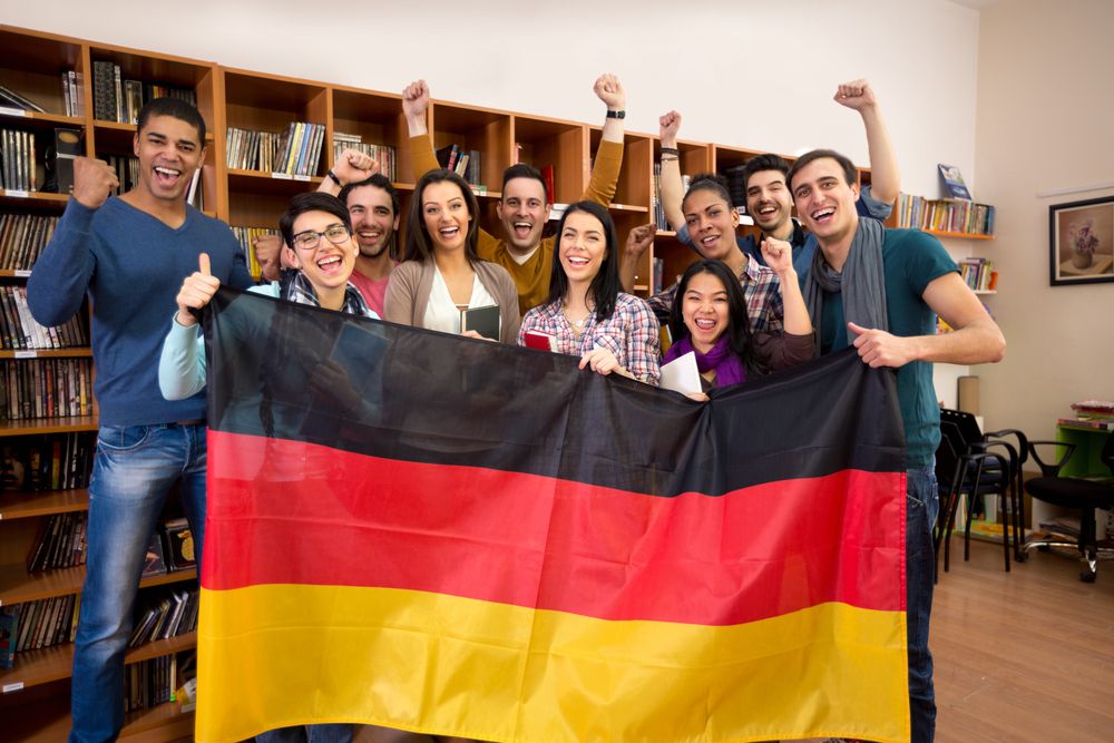 Excited,Students,With,Hands,Raised,And,Smiling,Faces,Present,Germany