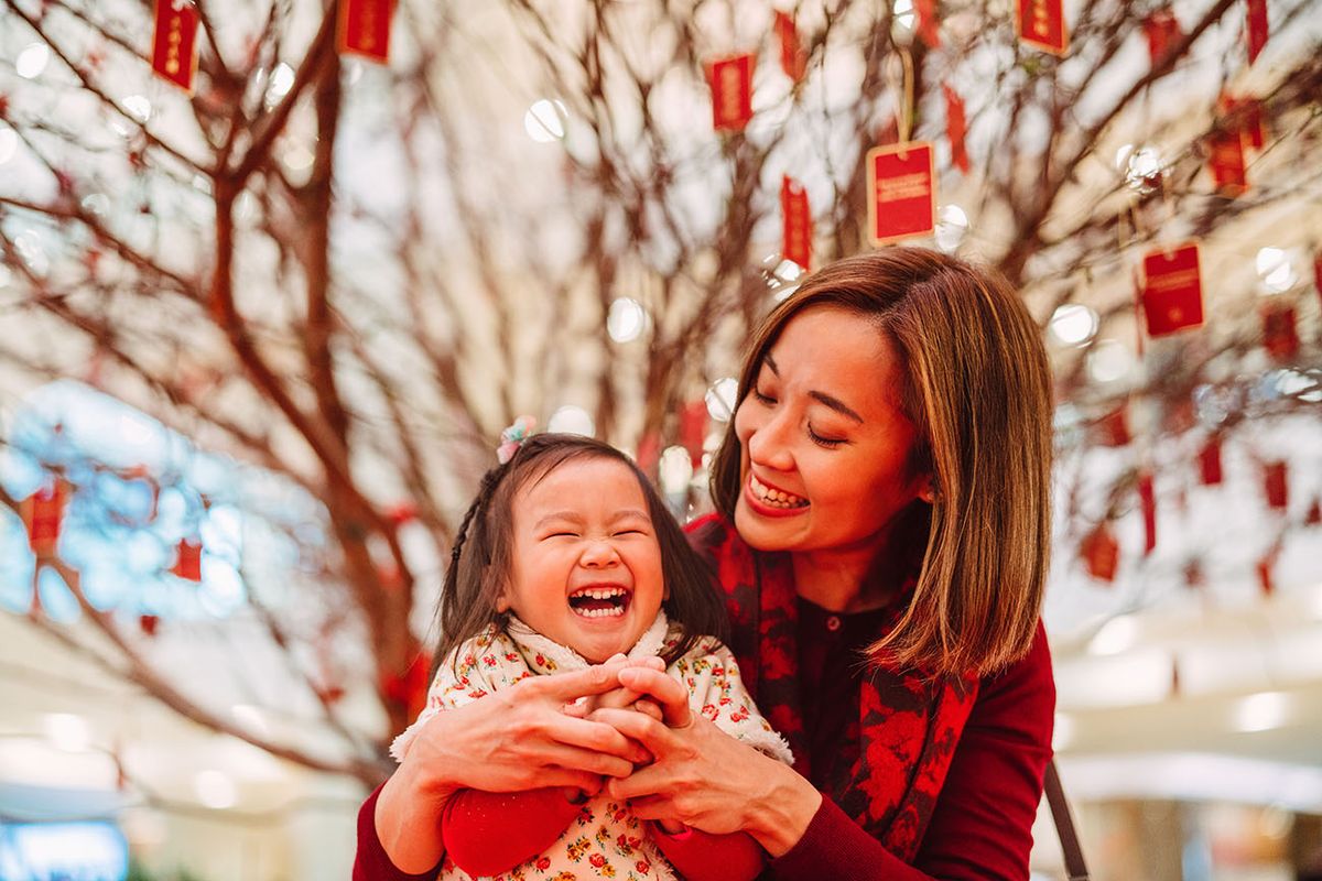 Pretty young mom making kung hei fat choy hand gesture with her lovely daughter joyfully in Chinese New Year Pretty young mom making kung hei fat choy hand gesture with her lovely daughter joyfully in front of the peach blossom tree in Chinese New Year