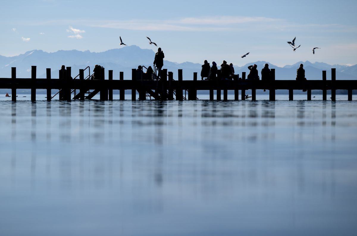 dpatop - 30 December 2022, Bavaria, Percha: People enjoying the beautiful weather on a jetty at Lake Starnberg. The Alps with the Zugspitze can be seen in the background.
