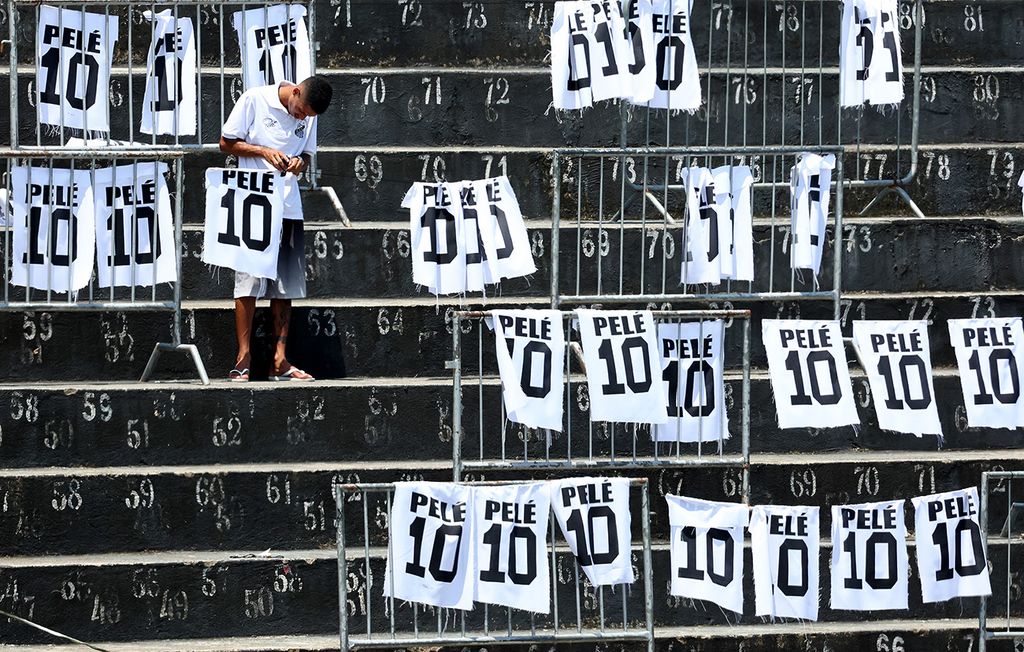 SANTOS, BRAZIL - JANUARY 02: A worker adjusts Pele signs at Urbano Caldeira Stadium during football legend Pele's funeral on January 02, 2023 in Santos, Brazil. Brazilian football icon Edson Arantes do Nascimento, better known as Pele, died on December 29, 2022 aged 82 after a battle with cancer in Sao Paulo, Brazil. The three-time World Cup champion with Brazil is considered one of the greatest soccer legends of all time. (Photo by Mario Tama/Getty Images)