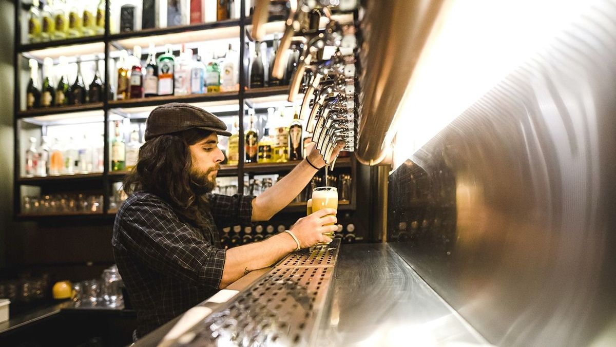 Side View Of Bartender Filling Beer Glass At Bar