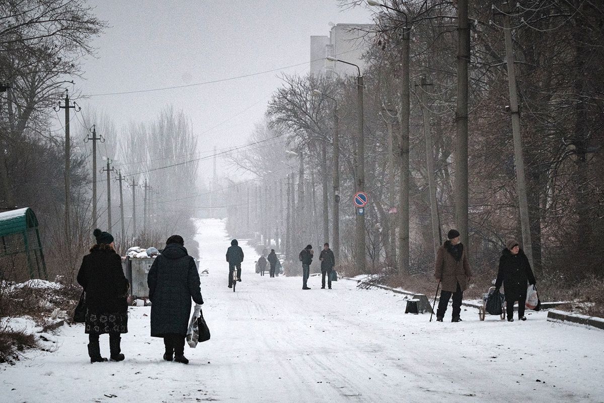  People walk along a snow covered street in Bakhmut, in the Donetsk region, on January 30, 2023, amid the Russian invasion of Ukraine. - The frontline city of Bakhmut has seen some of the heaviest fighting in recent months. (Photo by YASUYOSHI CHIBA / AFP)