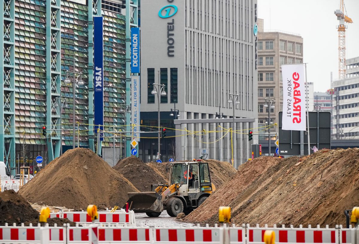 13 February 2023, Berlin: A construction machine works between mountains of sand on the Molkenmarkt construction site. In the background, the Rathauspassagen parking garage (l) can be seen, as well as the Motel One hotel and other commercial buildings on Alexanderplatz. According to a development plan adopted in 2016, urban restructuring is being carried out in the area in the Mitte district between Mühlendamm Bridge, Littenstrasse, Molkenmarkt, Klosterstraße and Spandauer Straße. Photo: Soeren Stache/dpa