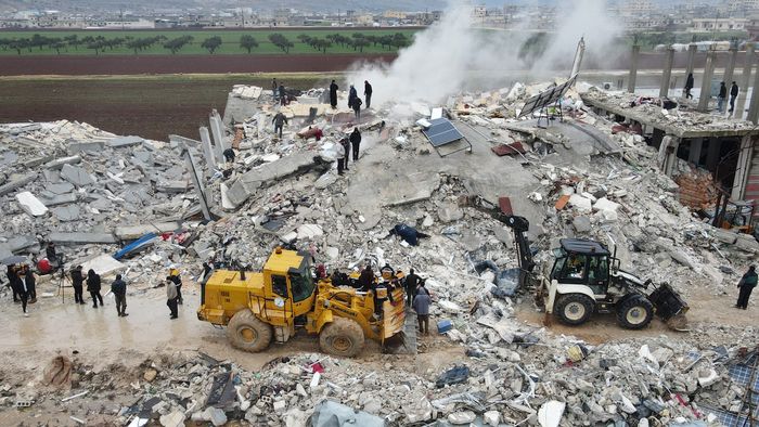 This aerial view shows residents helped by bulldozers, searching for victims and survivors in the rubble of collapsed buildings, following an earthquake in the town of Sarmada in the countryside of the northwestern Syrian Idlib province, early on February 6, 2023. - A 7.8-magnitude earthquake hit Turkey and Syria on February 6, killing hundreds of people as they slept, levelling buildings, and sending tremors that were felt as far away as the island of Cyprus and Egypt. (Photo by MUHAMMAD HAJ KADOUR / AFP)