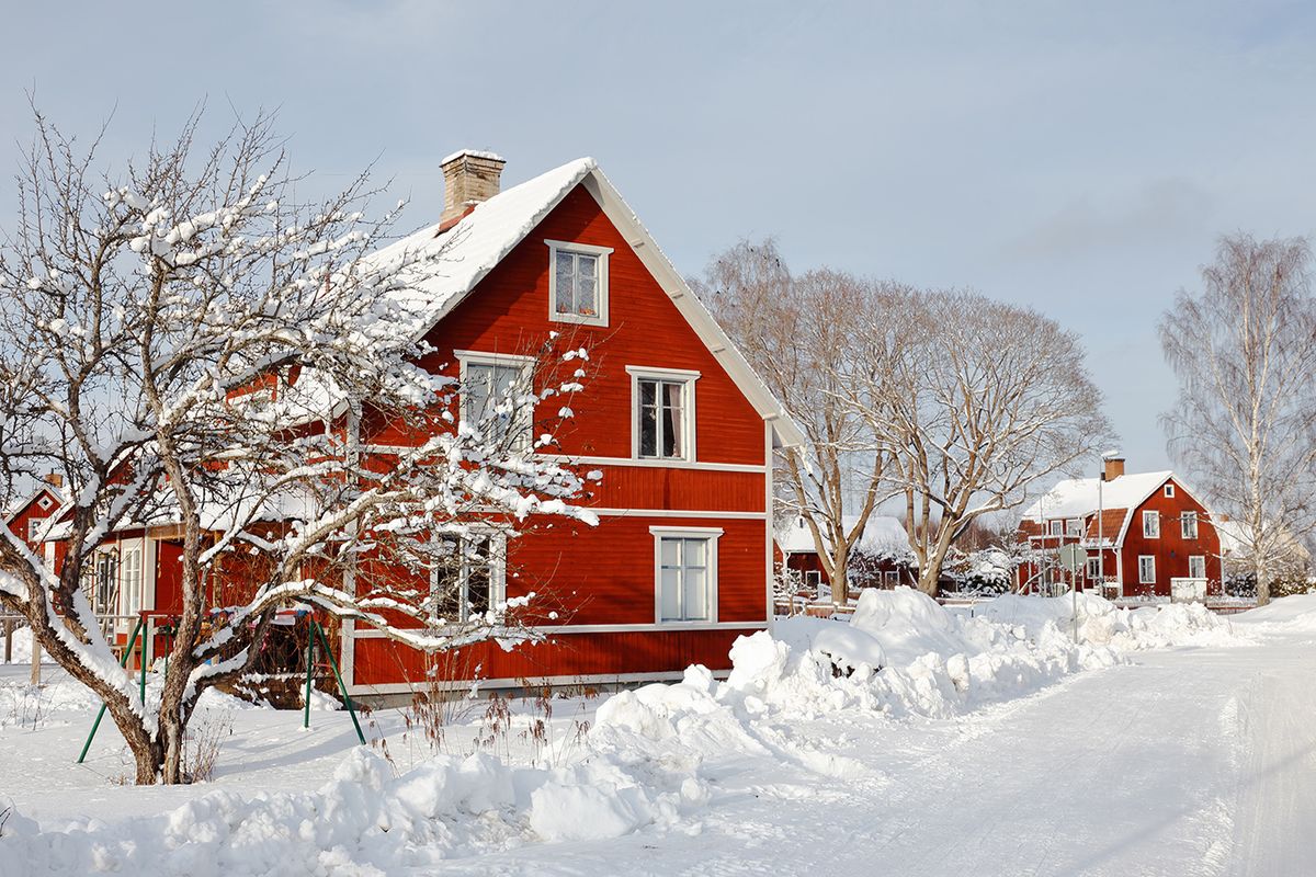 Swedish,Red,Two,Storeywooden,Family,Houses,Behind,A,Snow,Covered Swedish red two storeywooden  family houses behind a snow covered tree alongside the snow surfaced road in the residential area during the winter season.