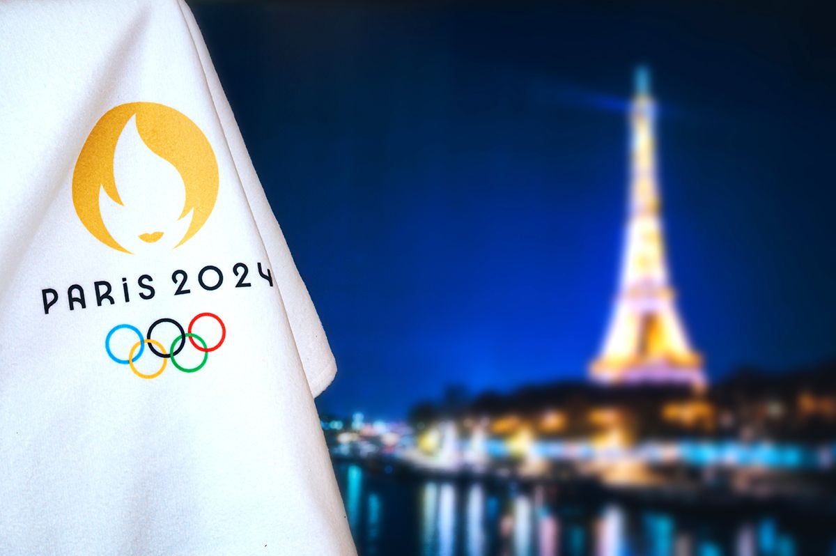Paris,,France,,August,8.,2022:,Summer,Olympic,Game,Paris,2024 PARIS, FRANCE, AUGUST 8. 2022: Summer olympic game Paris 2024 black background. Official logo of SOG 2024 in Paris on white blanket with dark City in night. Black edit space, sport event