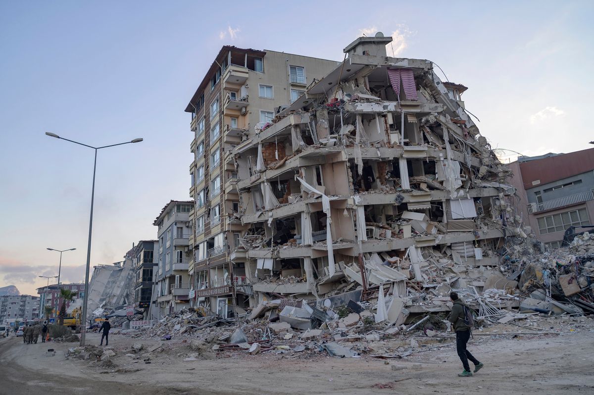 A man looks up at a collapsed building in Hatay, southern Turkey on February 19, 2023. - A  7.8-magnitude earthquake hit near Gaziantep, Turkey, in the early hours of February 6, followed by another 7.5-magnitude tremor just after midday. The quakes caused widespread destruction in southern Turkey and northern Syria and has killed more than 40,000 people.