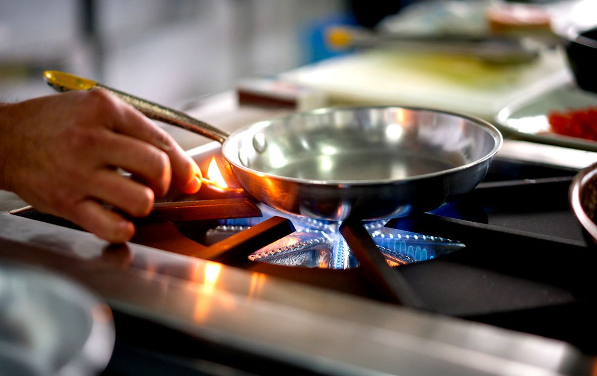 Chef lighting up a gas stove burner with a match Close-up on a chef lighting up a gas stove burner with a match while working at a restaurant
