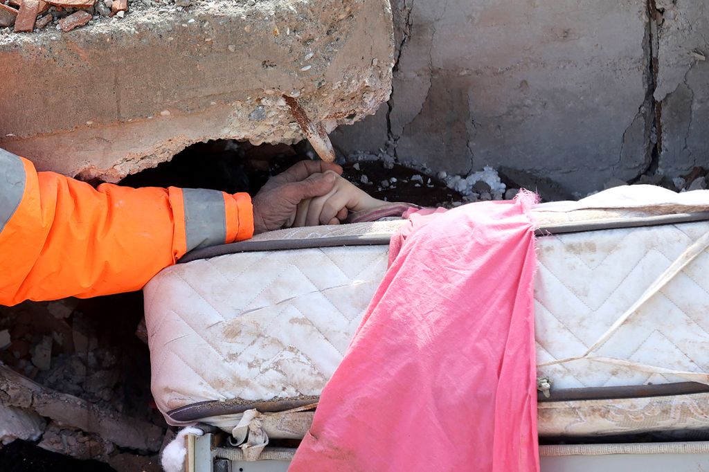 Mesut Hancer holds the hand of his 15-year-old daughter Irmak, who died in the earthquake in Kahramanmaras, close to the quake's epicentre, the day after a 7.8-magnitude earthquake struck the country's southeast, on February 7, 2023. - Rescuers in Turkey and Syria braved frigid weather, aftershocks and collapsing buildings, as they dug for survivors buried by an earthquake that killed more than 5,000 people. Some of the heaviest devastation occurred near the quake's epicentre between Kahramanmaras and Gaziantep, a city of two million where entire blocks now lie in ruins under gathering snow. (Photo by Adem ALTAN / AFP)