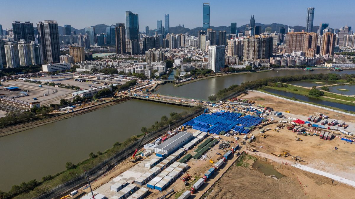 This aerial picture shows the construction site of a hospital to treat Covid-19 patients at the Lok Ma Chau loop at the Lok Ma Chau loop in Hong Kong, before the skyline of the southern Chinese city of Shenzhen on March 8, 2022.