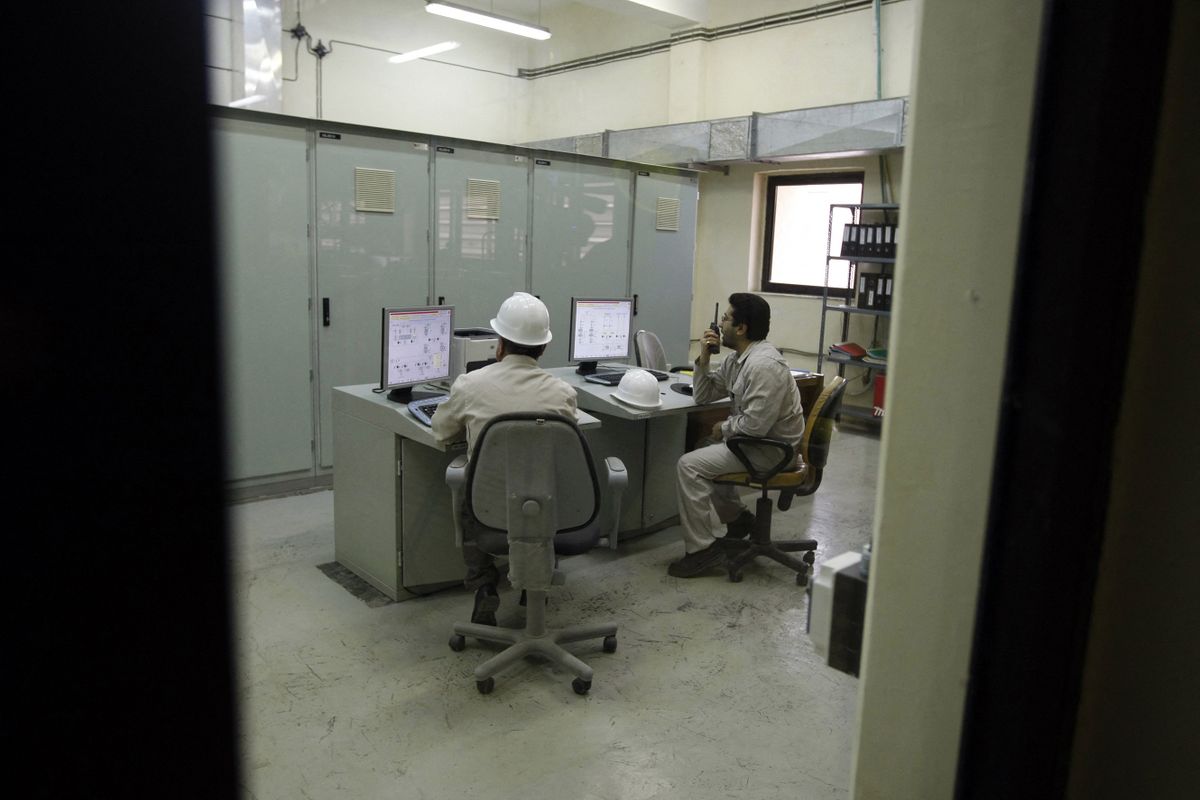 Iranian and Russian technicians work at the operation room of the water purifying facility at the Bushehr nuclear power plant in the Iranian port town of Bushehr, 1200 Kms south of Tehran, on February 25, 2009. Iran's first nuclear power plant, which was undergoing tests on February 25 after construction was completed by Russia, has been delayed for more than three decades. AFP PHOTO/BEHROUZ MEHRI 