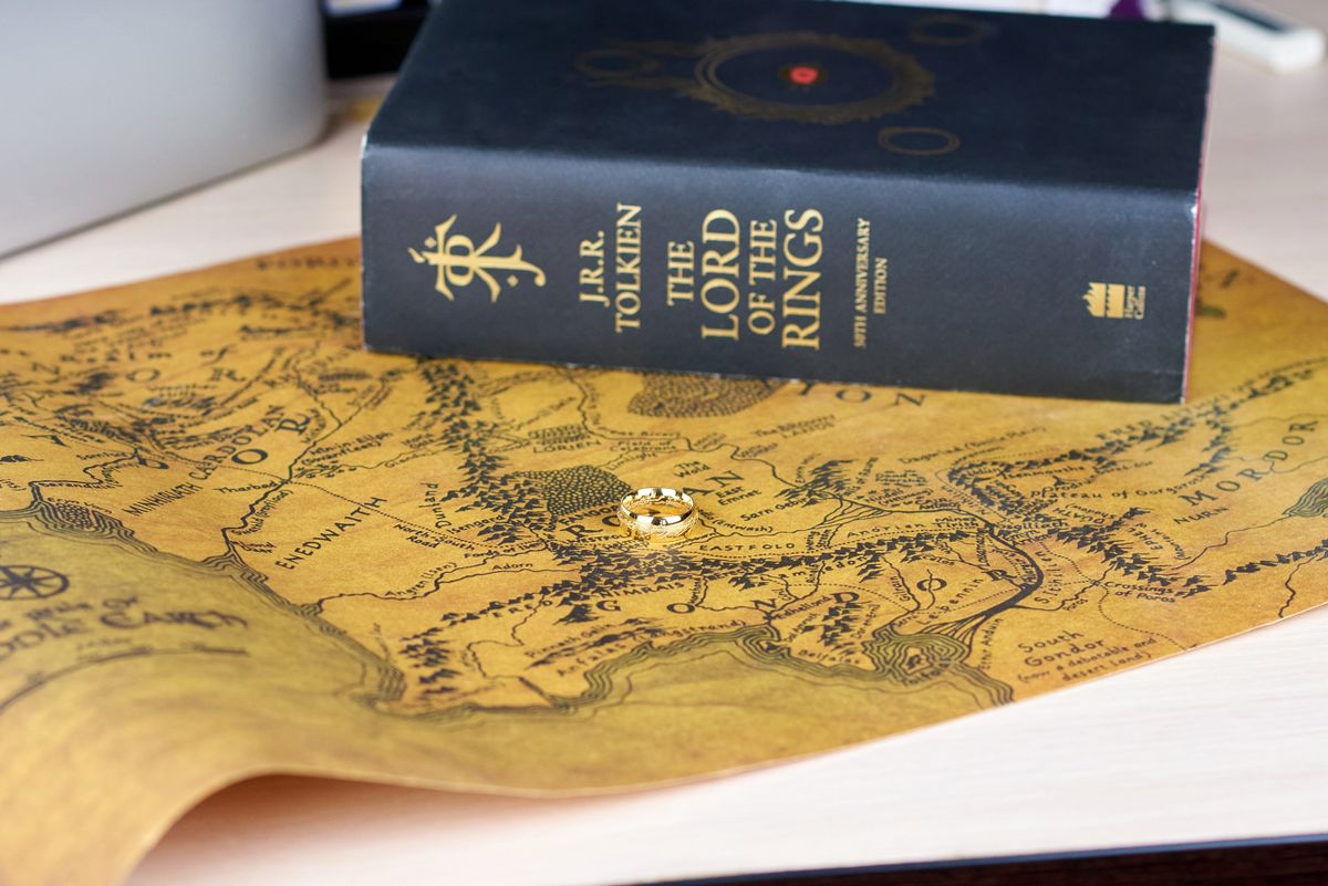 Astrakhan, Russia - 11.09.2022: Golden Ring of Power lies on the map of Middle-Earth besides The Lord of the Rings book