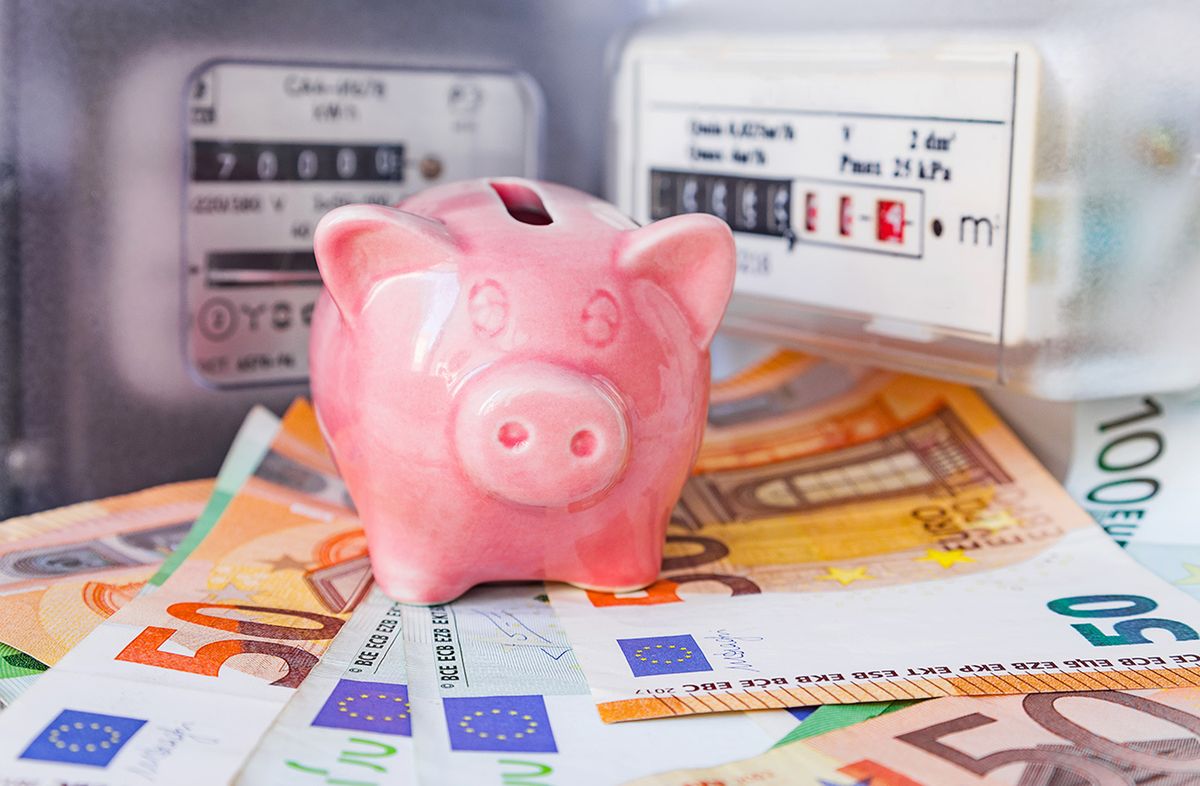 Piggy,Bank,And,Euro,Cash,Near,An,Electricity,Meter,And Piggy bank and Euro cash near an electricity meter and gas meter. Utility bills, consumption of electricity and gas for heating home, energy costs, symbolic image.