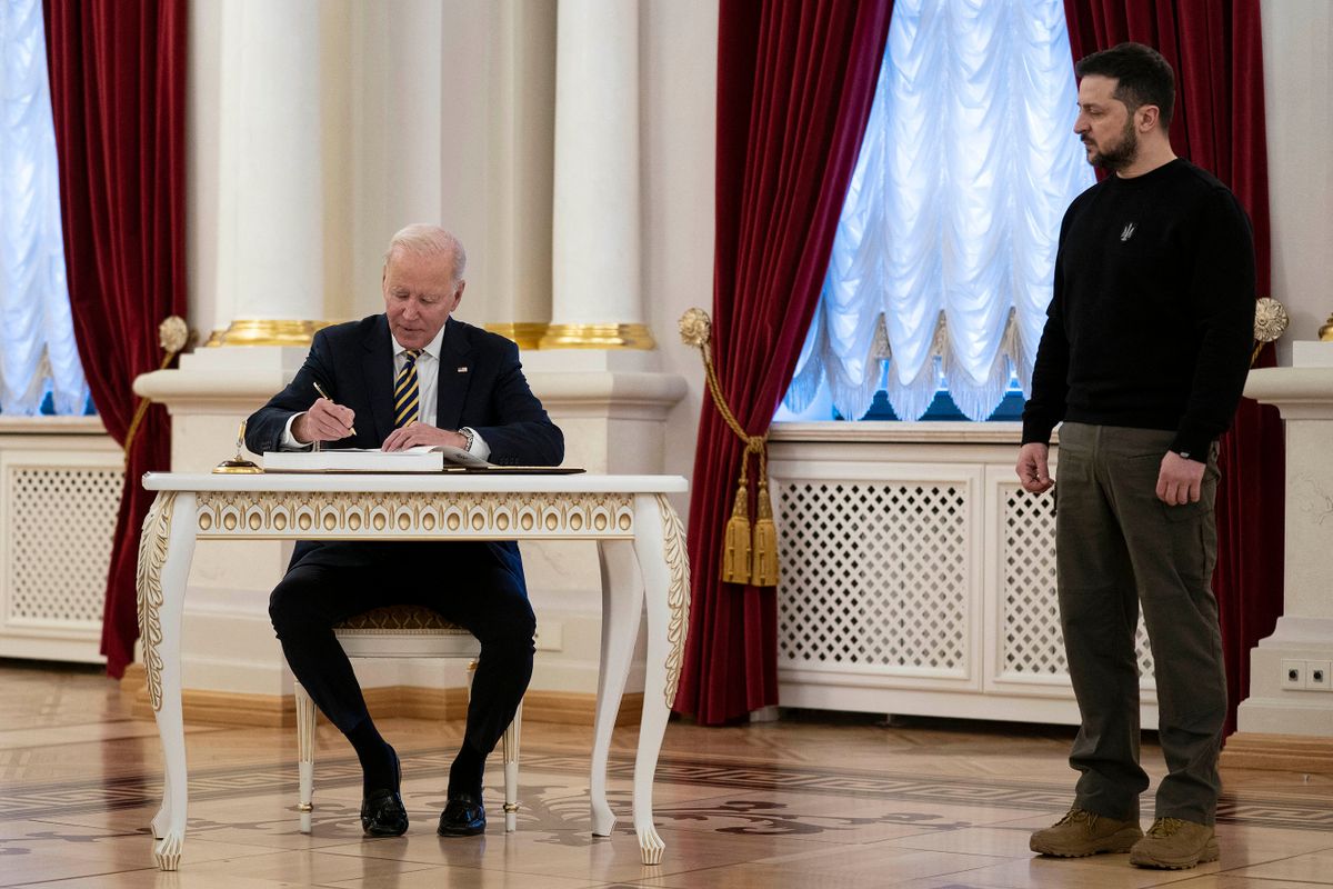 US President Joe Biden (L) signs the guest book during a meeting with Ukrainian President Volodymyr Zelensky (R) at the Mariinsky Palace in Kyiv on February 20, 2023. - US President Joe Biden promised increased arms deliveries for Ukraine during a surprise visit to Kyiv on February 20, 2023, in which he also vowed Washington's "unflagging commitment" in defending Ukraine's territorial integrit