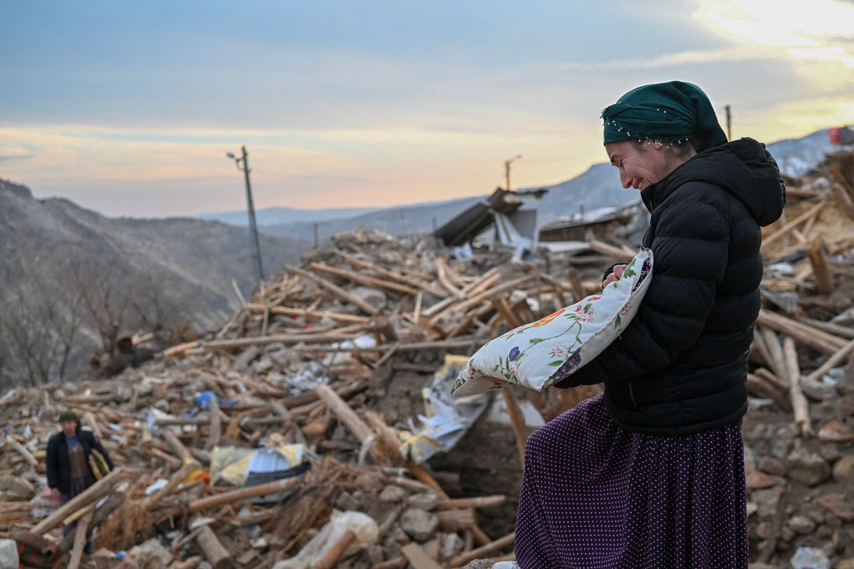 This photograph taken on February 19, 2023, shows a woman crying as she collects her personal belongings atop the rubble of her collapsed house in Yaylakonak village in Adiyaman district, a Kurdish alevi community village where 108 people died and 170 houses collapsed after a 7.8-magnitude earthquake struck parts of Turkey and Syria. - A 7.8-magnitude earthquake hit near Gaziantep, Turkey, in the early hours of February 6, followed by another 7.5-magnitude tremor just after midday. The quakes caused widespread destruction in southern Turkey and northern Syria and has killed more than 40,000 people. (Photo by BULENT KILIC / AFP)
