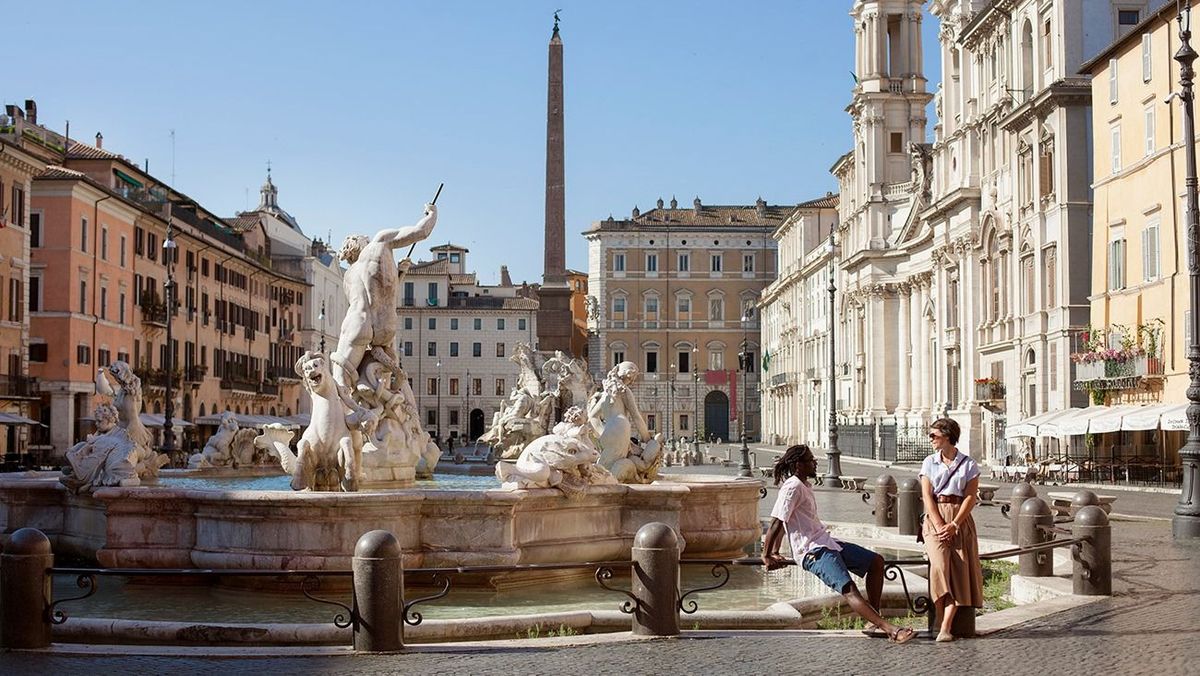 Man and woman at Bernini fountain in beautifully deserted Piazza Navona, Rome, Italy