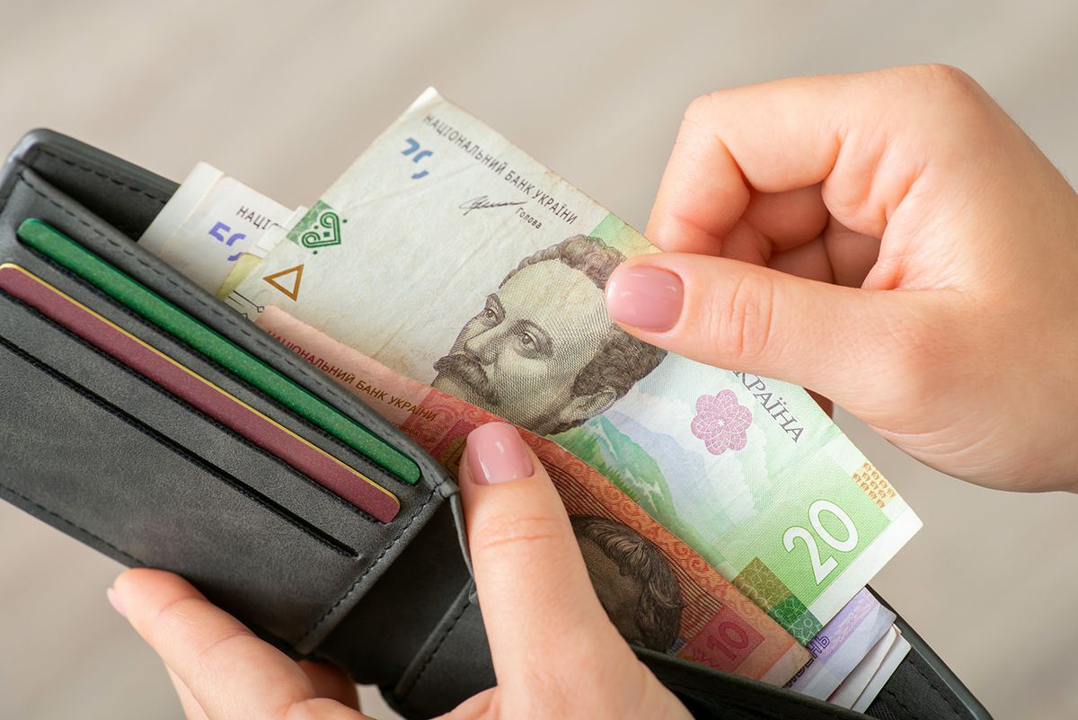 Small money in the wallet, paying for goods concept Woman dealing with finances, using ukrainian hryvnias while shopping
