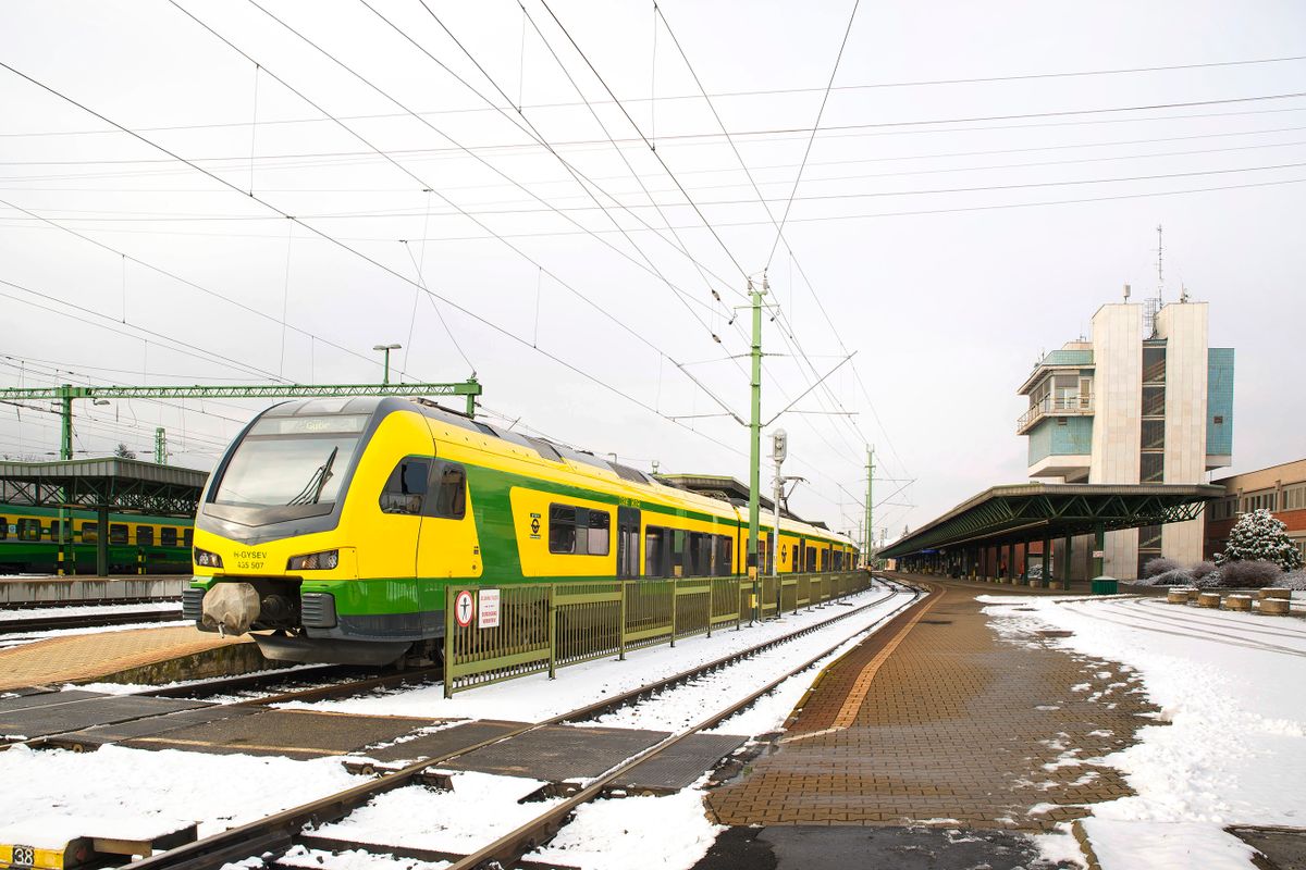 Sopron, 2022. január 24.A Győr-Sopron-Ebenfurti Vasút (GYSEV), Stadler FLIRT típusú személyszállító vonata indul Győr felé a vasúttársaság soproni páyaudvaráról. A GYSEV 1872-ben kiadott engedély-okmánya rendelkezett arról, hogy vasútvonal épüljön Győrtől Sopronon át egészen Ebenfurtig. A soproni állomás 1876-ban létesült a GYSEV új állomásaként. A világháborúban elpusztított és azután csak hellyel-közzel helyreállított régi felvételi épületet lebontották és helyére Szántó Gyula építész tervei alapján modern vasútállomás létesült, melyet 1977-ben adtak át és 2020-ban teljesen felújították (jobbra). A városi vasútállomásnak kitüntetett szerepe van, hiszen nemcsak, hogy Sopronban van a vasúttársaság székhelye, de Budapesten kívül ez az egyetlen város az országban, ahonnan vonattal Bécsbe és Pozsonyba is el lehet jutni.