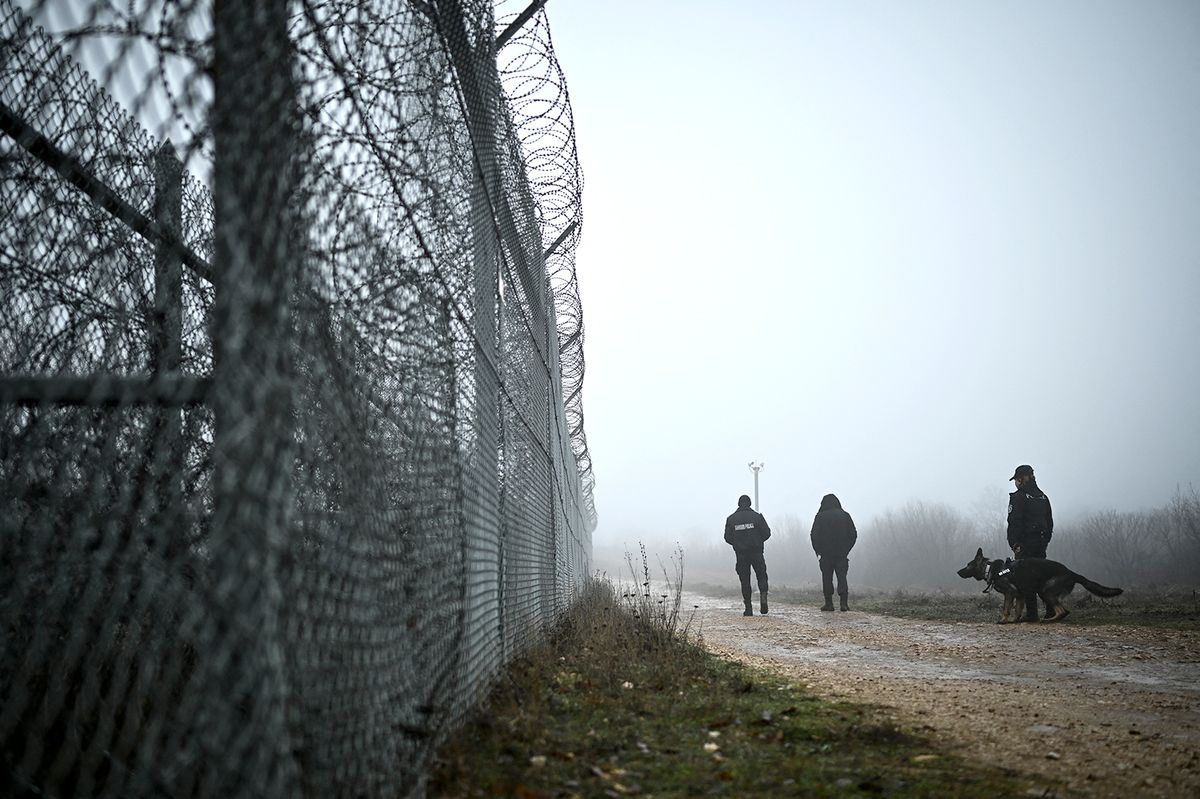 Bulgarian border police officers patrol with a dog in front of the border fence on the Bulgaria-Turkey border near the village of Lesovo on January 13, 2023. - Bulgaria faces mounting accusations that it is abusing people trying to cross its border with Turkey, with asylum seekers saying they have been pushed back, locked up, stripped and beaten. The EU member serves as a gateway into the bloc and is trying to tighten the border to stop a rising number of people seeking to cross, which has reached levels unseen since 2015. (Photo by Nikolay DOYCHINOV / AFP)
